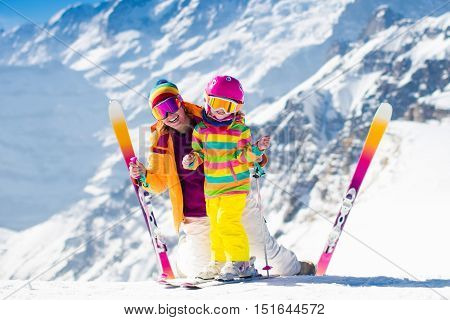 Family ski vacation. Group of skiers in Swiss Alps mountains. Mother and child skiing in winter. Parents teach kids alpine downhill skiing. Ski gear and wear safe helmets.