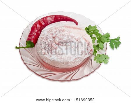 Frozen roll of pork belly covered by frost chili pepper and twig of cilantro on a pink glass dish on a light background