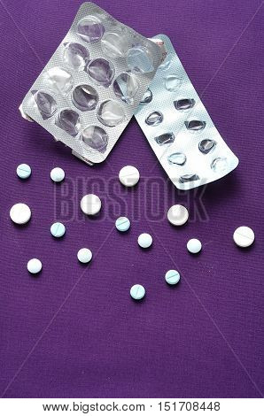 Medicine pills on Purple background with a empty pill blister packs. Drug prescription for treatment medication. Pharmaceutical medicament cure in container for health.