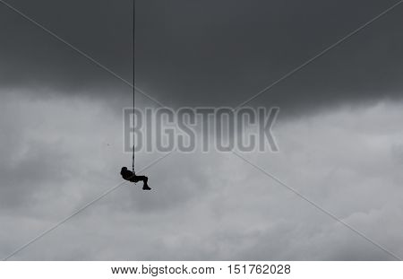 Ropejumper hanging on a rope and waitng for landing against the backdrop of an overcast autumn sky