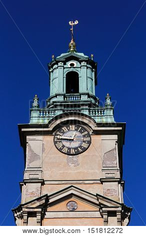 Close-up of the Stockholm Cathedral (Storkyrkan) tower with clock against a blue sky.