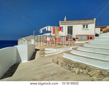 House and wall above the ocean on coastline of Peniche, Portugal