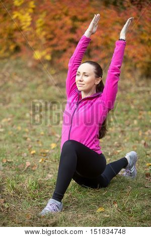 Portrait of sporty beautiful happy young woman practicing fitness, standing in low lunge exercise on her knee, warming up, stretching before morning running routine, working out outdoor on autumn day