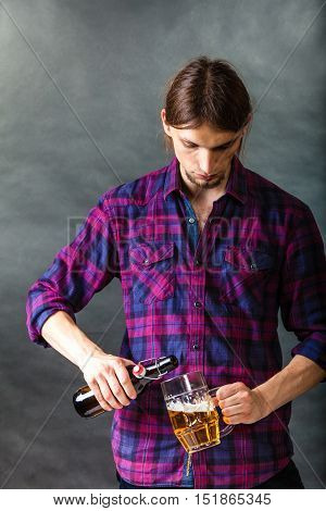 Alcohol liquor drinking relax party concept. Tapster fills stein from bottle. Young male bartender empties beer into glass.