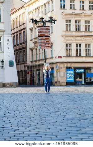 Woman looks at map in the old town square. Travel guide, tourism in Europe, female tourist with map. Kostel Panny Marie pred Tynem. Church of the Virgin Mary.