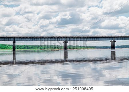 Steel Bridge With Lots Of Clouds In The Sky And Their Reflection In Water