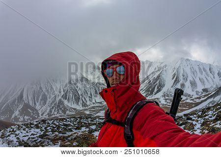 Selfi Male Mountaineer In Snowy Mountains, Wearing A Helmet With A Backpack.