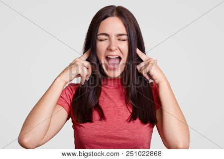 Annoyed Brunette Woman Asks To Stop This Sound, Pluggs Ears With Both Index Fingers, Exclaims Angril