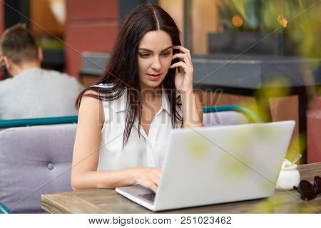 Concentrated Young Businesswoman Looks Attentively At Screen Of Laptop Computer, Surfes Webpages, Re