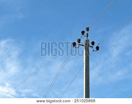 Power Pole On Blue Sky Background With White Clouds. Power Transmission Line With Electrical Wires A