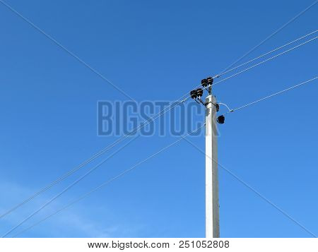 Power Line Support Isolated On Blue Sky Background. Power Pole With Electrical Wires And Capacitors,