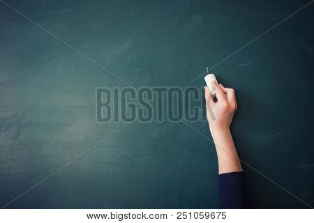 Children's Hand Writes Chalk On Green Blackboard In Classroom