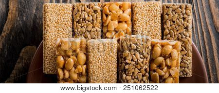 Kozinaki With Seeds, Nuts, Sesame And Honey. On A Dark Wooden Background. Long Wide Banner.