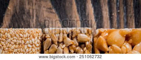 Kozinaki With Seeds, Nuts, Sesame And Honey. On A Dark Wooden Background. Long Wide Banner.