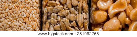 Kozinaki With Seeds, Nuts, Sesame And Honey. On A Dark Wooden Background. Long Wide Banner.