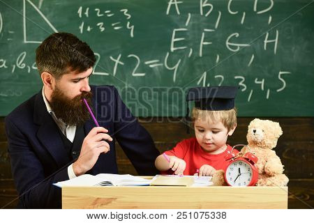 Hometask Concept. Father Checking Hometask, Helps To Boy, Son. Teacher In Formal Wear And Pupil In M