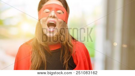 Middle age super hero woman wearing red mask and cape stressful, terrified in panic, shouting exasperated and frustrated. Unpleasant gesture. Annoying work drives me crazy