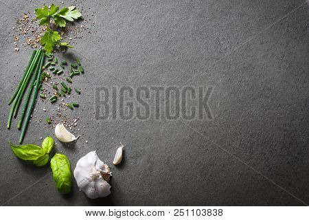 A Top Down View On Kitchen Ingredients Like Garlic, Basil, Spices And Herbs On Slate Stone, With Fre