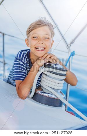 Cute Boy On Board Of Sailing Yacht On Summer Cruise. Travel Adventure, Yachting With Child On Family