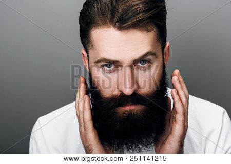 Cropped Horizontal Close Up Portrait Of Brutal Handsome Young Bearded Male Corrects His Moustache An