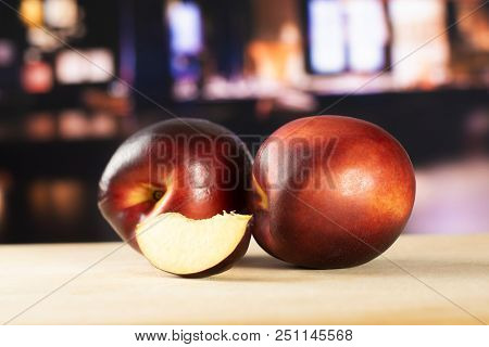 Group Of Two Whole One Slice Of Ripe Deep Red Nectarine With Restaurant In Background