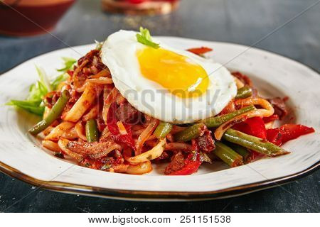 Homemade Kaurma Lagman or Laghman with Vegetables, Beef Meat and Oriental Spices Close Up. Rich Asian Dish of Fried Home-Made Noodles Prepared from a Stringy Dough, Served with Egg