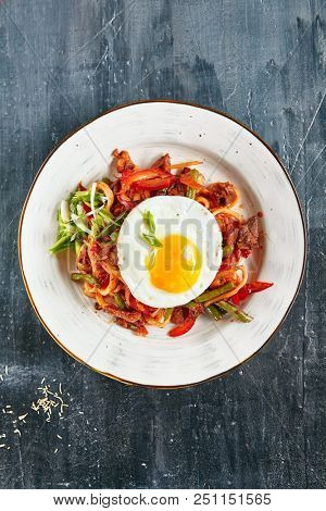 Homemade Kaurma Lagman or Laghman with Vegetables, Beef Meat and Oriental Spices Close Up. Rich Asian Dish of Fried Home-Made Noodles Prepared from a Stringy Dough, Served with Egg Top View