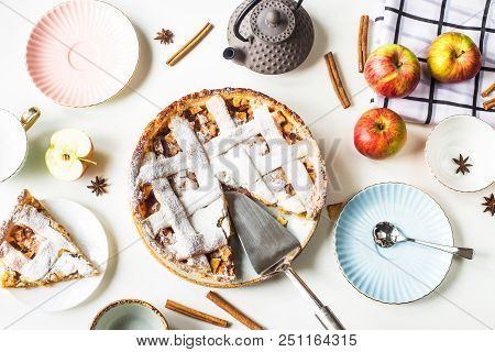 Homemade Apple Pie Sprinkled With Powdered Sugar In Female Hand On A White Table Next To Apples, Cin