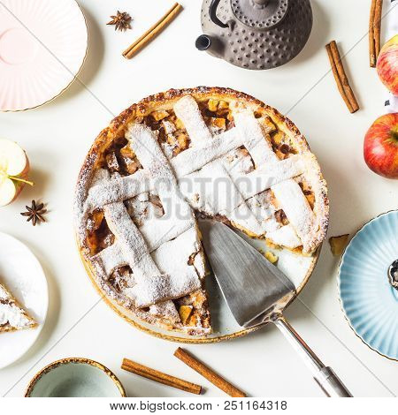 Homemade Apple Pie Sprinkled With Powdered Sugar In Female Hand On A White Table Next To Apples, Cin