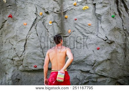 Photo from back of brunet climber on background of boulder for rock climbing