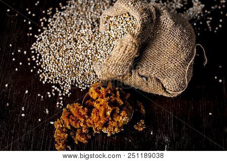 Close Up Of Raw  Dried Grains Of Pearl Millet With Jaggery Or Gud On A Wooden Surface In Drak Gothic