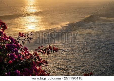 Waves And Red Flowers On Sunset In Bali Asia