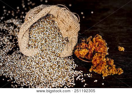 Close Up Of Raw  Dried Grains Of Pearl Millet With Jaggery Or Gud On A Wooden Surface In Drak Gothic