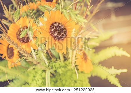 Bouquet Of Sunflowers In A Glass Vase On A Wooden Table. Retro Toned.