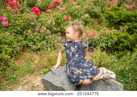 Portrait Of Alone Girl Sitting On The Stone In Park