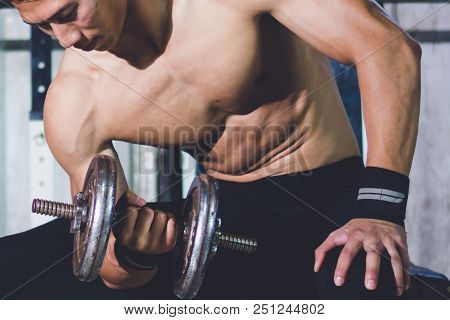 Strong Athletic Man Doing Exercises With Dumbbells In Local Gym