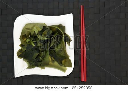 Japanese wakame seaweed food with on bamboo background with red chopsticks. Has many health benefits and is very high in minerals.