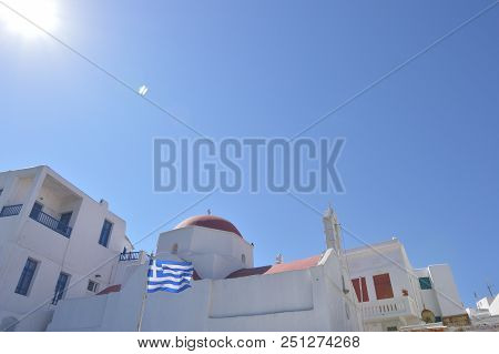Picturesque Red Roofs And The Flag Of Greece In Chora On The Island Of Mykonos. Architecture Landsca