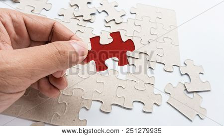 Hand Put Missing Jigsaw Puzzle Into The Paper Board