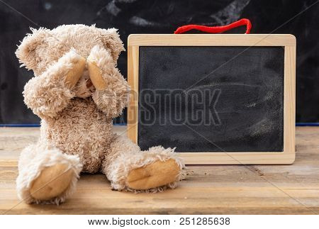 Teddy Bear Covering Eyes And A Blank Blackboard, Space For Text