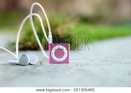 Pink Music Device With White Ear Plugs In The Ground
