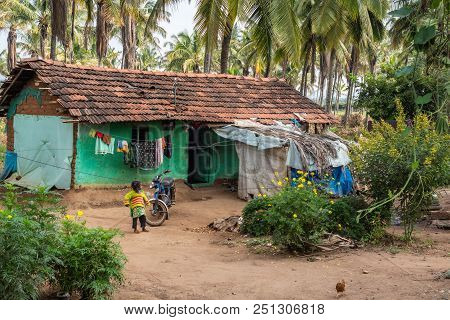 Belathur, Karnataka, India - November 1, 2013: Little Girl Plays In Front Of Green Peinted Humble Dw