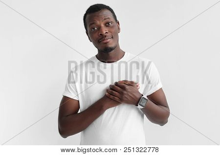 Positive Cheerful African American Man Keeps Hands On Heart, Expresses Good Feelings To People, Isol