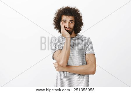 Portrait Of Sad Bothered Hispanic Guy With Cool Afro Hairstyle, Leaning Face On Palm And Looking Wit