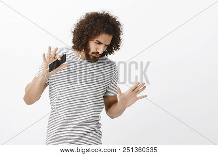 Studio Shot Of Thrilled Carefree Handsome Male Model With Beard And Afro Hairstyle, Dancing And Look