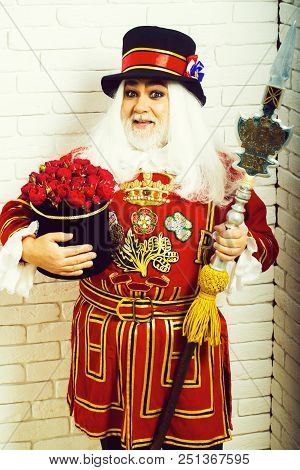 Amazed Senior Man Beefeater Yeomen Warder Or Male Royal Guard Bodyguard In Red Uniform With Flowers 