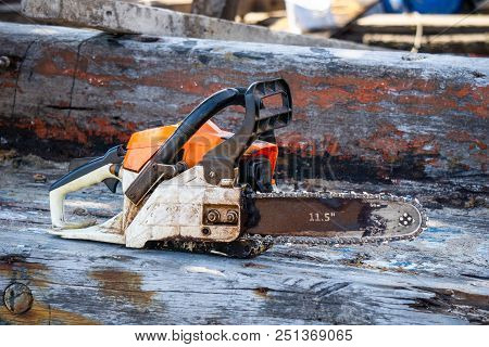 Orange Gasoline Engine Portable Chainsaw Put On The Old Wooden Plank