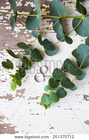 Wedding Rings On A White Old Table With A Sprig Of Eucalyptus