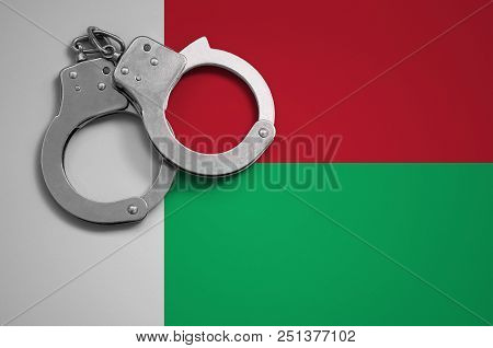Madagascar Flag  And Police Handcuffs. The Concept Of Crime And Offenses In The Country.