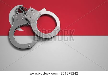 Singapore Flag  And Police Handcuffs. The Concept Of Crime And Offenses In The Country.